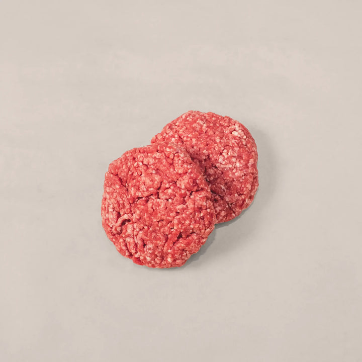 Two hand-formed raw beef patties made from 100% premium Canadian beef, ready for grilling.