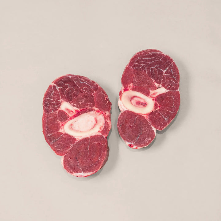 Hand-cut veal shanks for osso buco, showcasing marbling and a rich red color, ideal for gourmet cooking.
