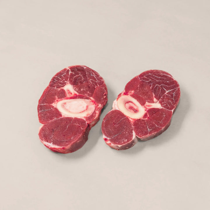 Hand-cut veal shanks for osso buco, showcasing rich marbling and connective tissue.
