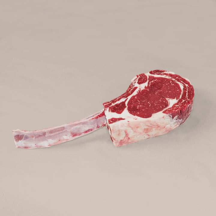 Heavy Duty Beef Tomahawk Steak with a long bone and marbled body, perfect for a dramatic centerpiece.